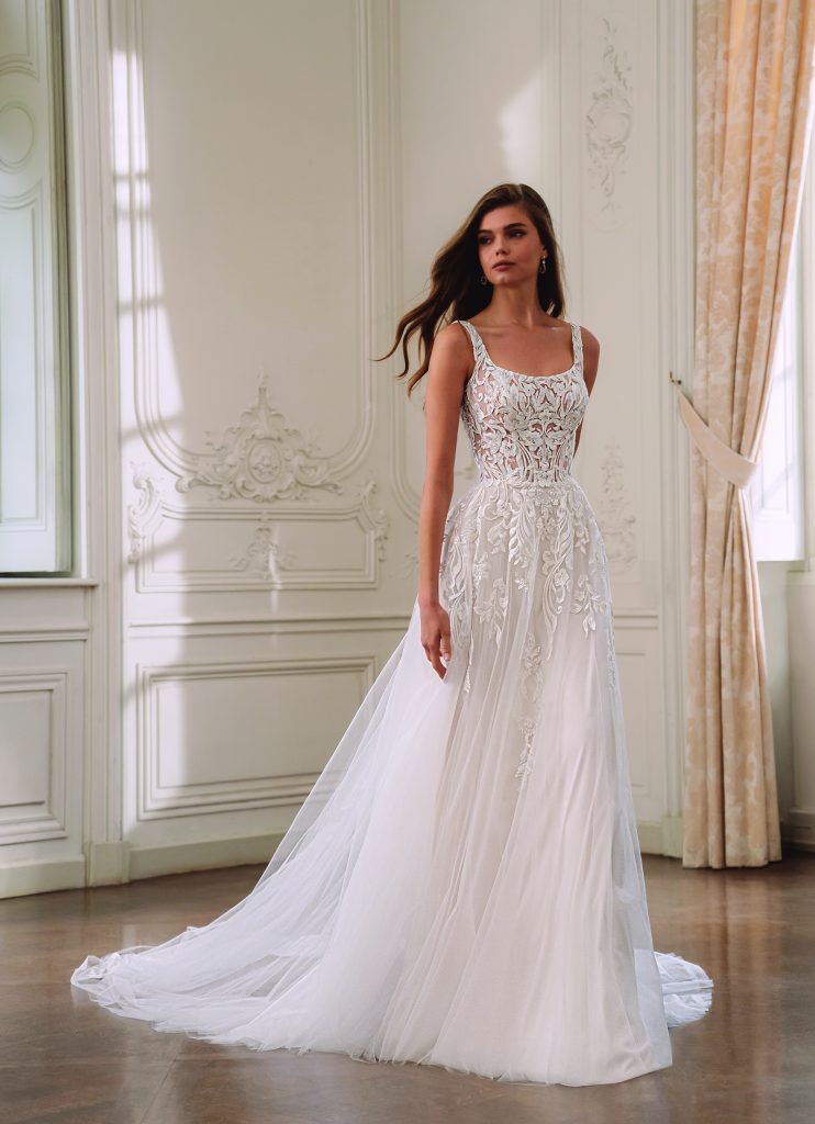 Luchtige A-lijn bruidsjurk met rijk kantborduursel en subtiele pailletten, gefotografeerd in een elegante, klassieke interieursetting.