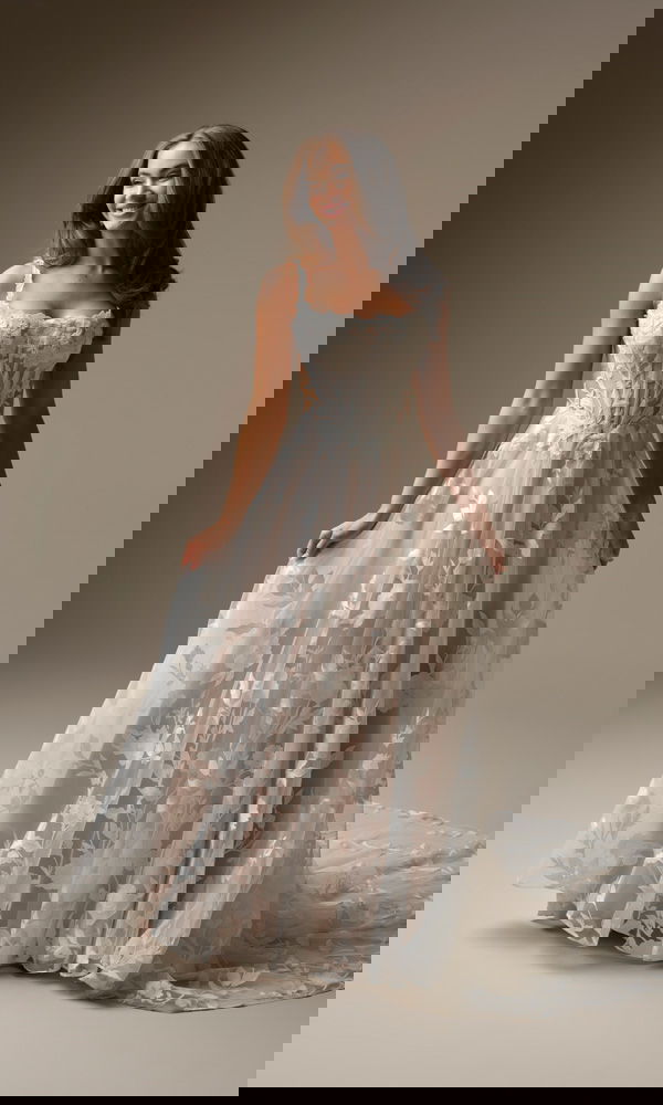 Lächelnde Braut in einem floralen A-Linien-Kleid mit Korsagen-Oberteil und transparentem Spitzenrock.