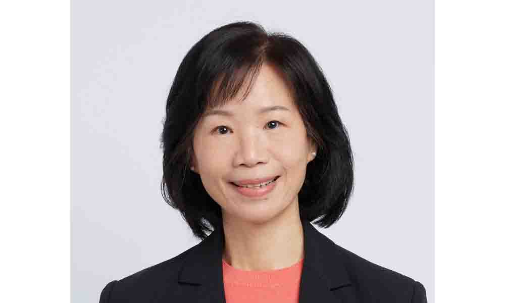 Porträt einer Frau mit schulterlangem dunklem Haar, die freundlich in die Kamera lächelt und einen dunklen Blazer trägt.