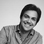 Natürliches Schwarz-weiß-Porträt einer Person mit offenem Lächeln, entspannt in die Kamera blickend.