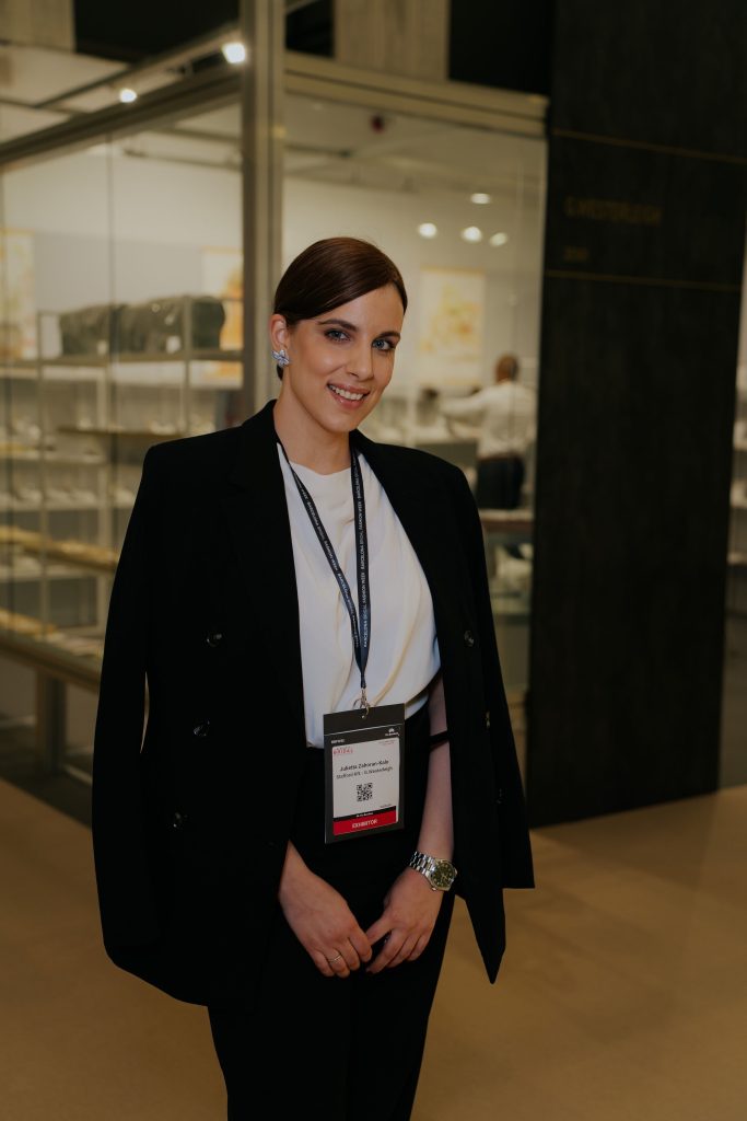 Frau im Businesslook mit Event-Badge steht auf einer Messe oder Branchenveranstaltung